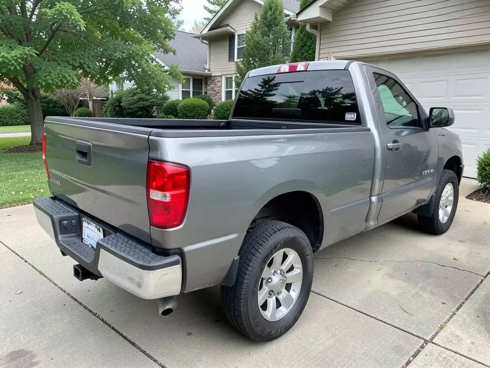 AI-drawn sample: a gray pickup truck seen from the rear left corner, showing the tailgate and bed, parked in a driveway beside a house