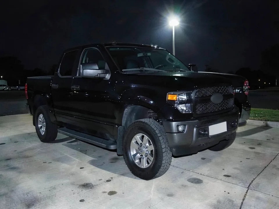 AI-drawn sample: a black full-size pickup truck on a concrete lot at night under a flood light